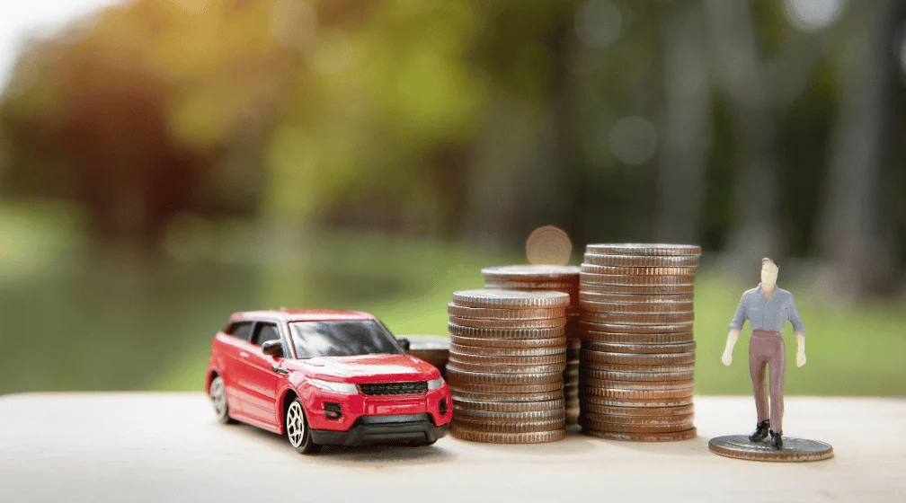 Imagem de carro miniatura ao lado de pilhas de moedas para ilustrar artigo sobre a importância de manter o IPVA em dia