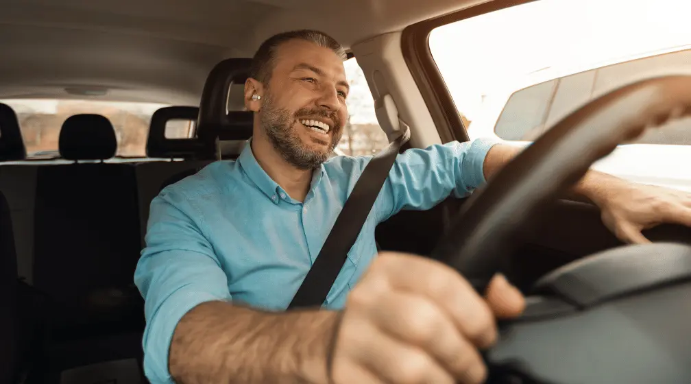 Imagem de um homem dirigindo com expressão alegre para ilustrar artigo sobre free flow na rodovia Padre Manoel da Nóbrega
