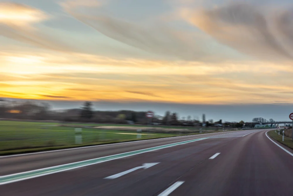 Estrada vazia com faixa verde e céu ao pôr do sol. Conteúdo sobre free flow na BR-470