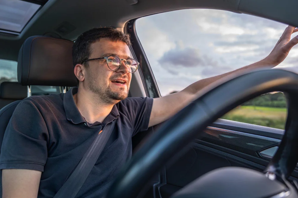Homem dirigindo carro com cinto de segurança e olhando para fora da janela em dia nublado. Conteúdo sobre free flow na serra gaúcha